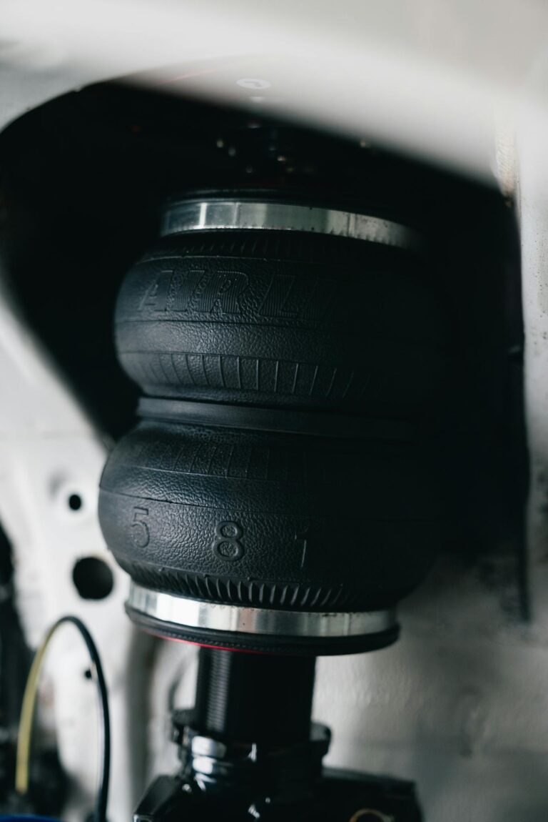 Detailed image of a car suspension system featuring an air spring with visible branding, highlighting automotive engineering.